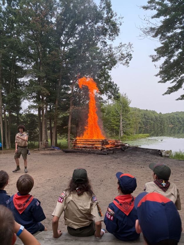 Scouts watching a campfire demonstration near the lake