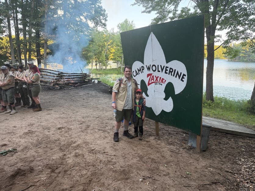 Two adults and a Scout posing at the Camp Wolverine gateway