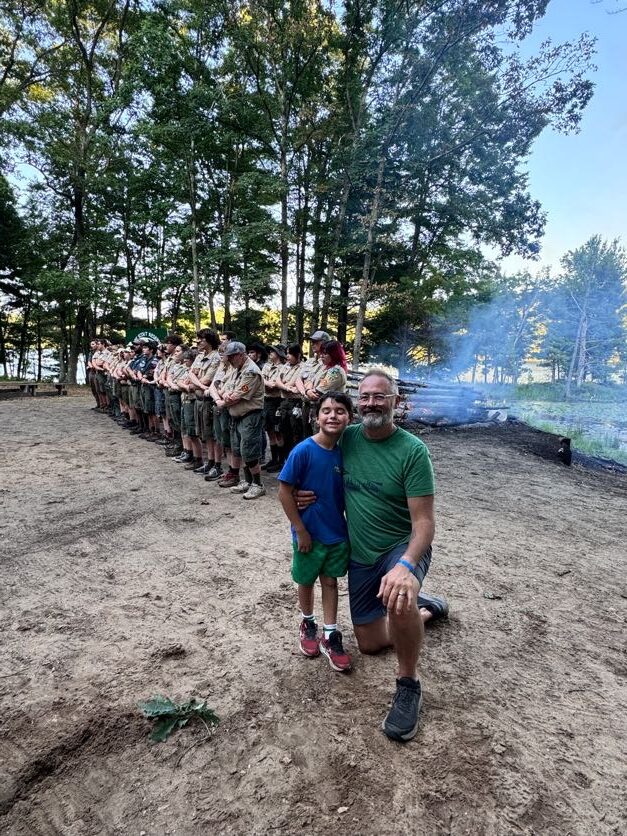Scouts standing near a campfire by the lake